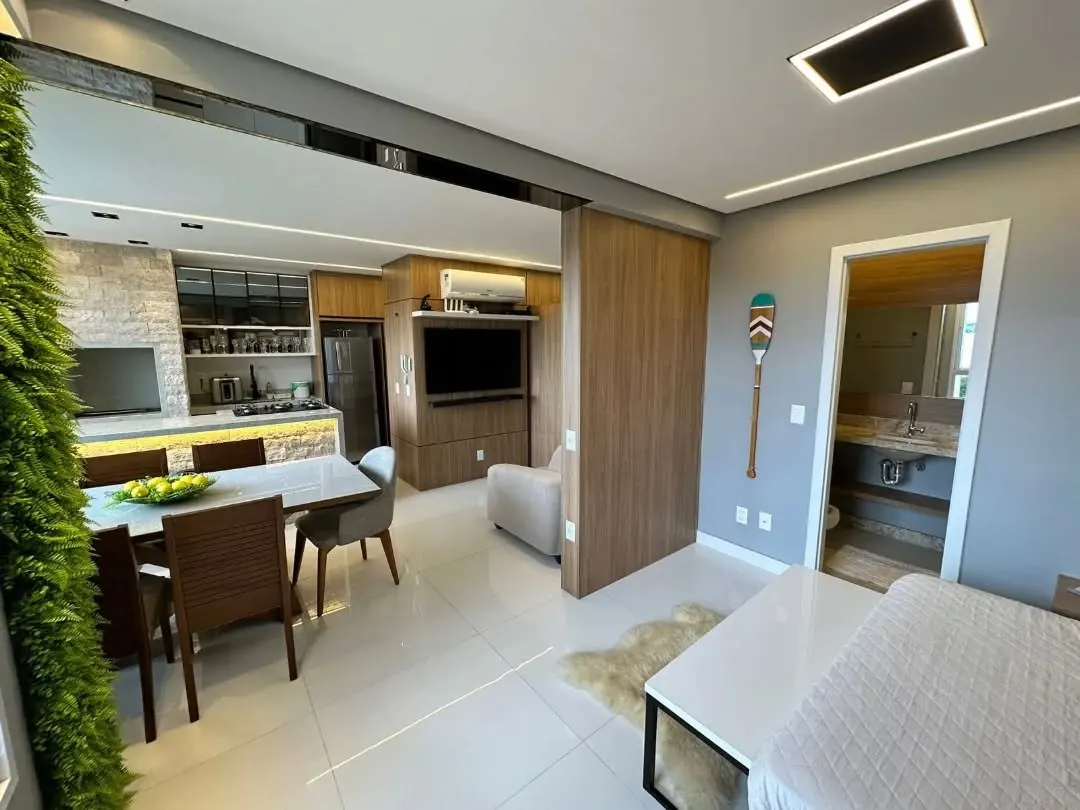Apartamento integrado com sala de jantar, cozinha, painel de TV em madeira e armários