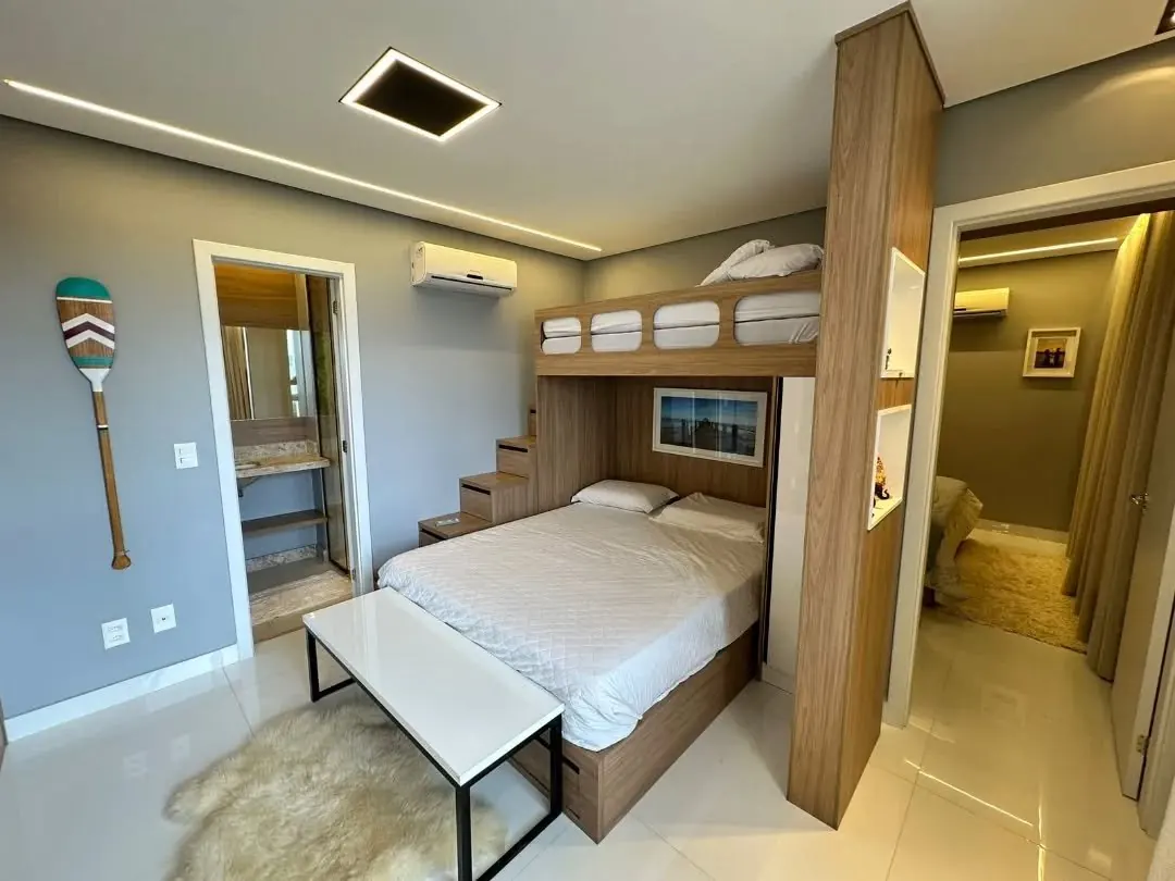 Quarto com cama de casal e beliche em madeira sobre ela, com escada de gavetas