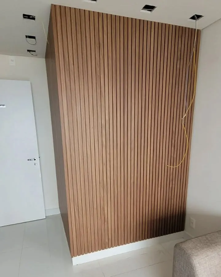 Painel ripado de madeira do chão ao teto em uma sala, com spots de embutir no teto