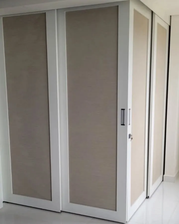 Armário com portas de correr brancas e painéis em tecido bege