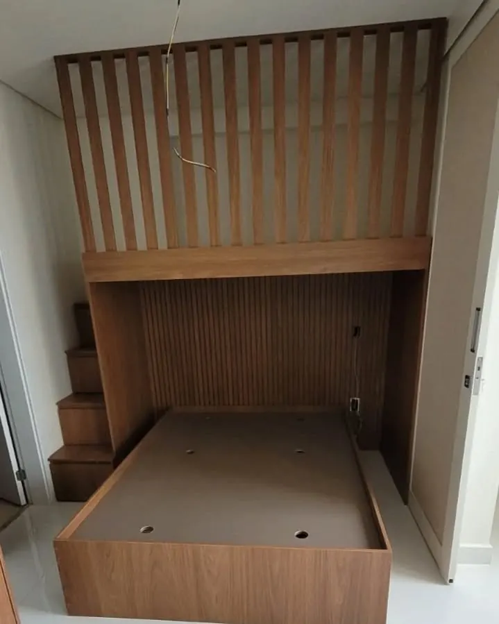 Cama box em madeira com mezanino ripado e escada lateral, em vista frontal
